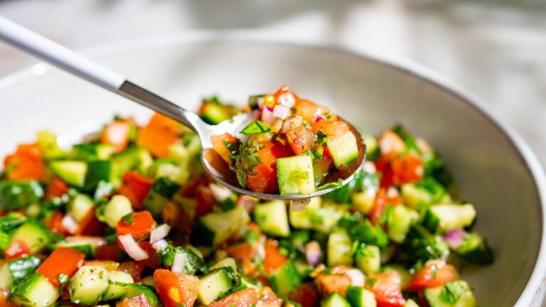 Shirazi salad is taken from a bowl with a spoon.