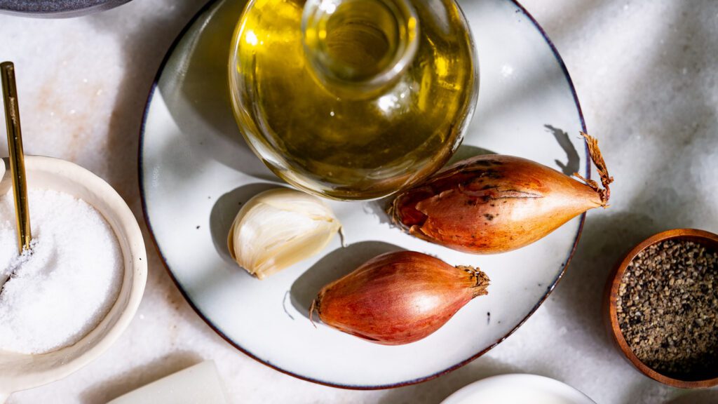 Olive oil, garlic, shallots on a small plate.