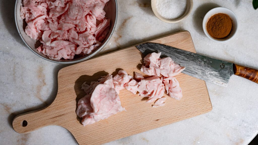 Lamb fat is cut into pieces for awarma on a wooden board.