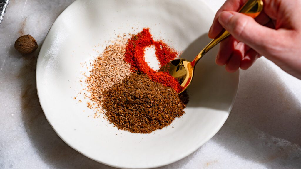 Spices for baharat are mixed in a bowl.