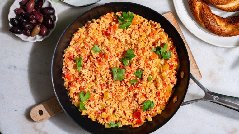 Menemen - Türkische Rührei in der Pfanne serviert. Daneben Brot und Oliven.