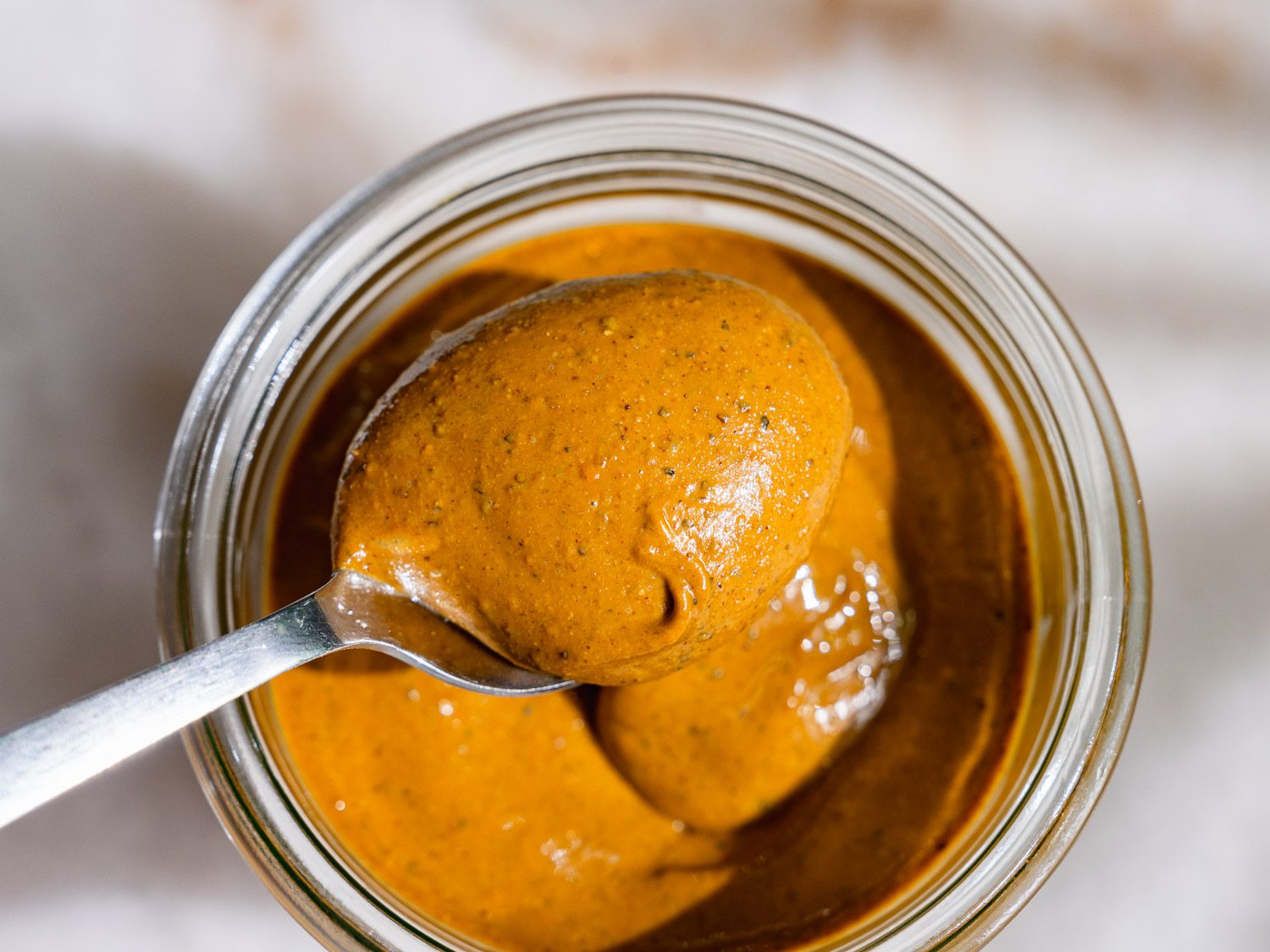 Homemade pistachio puree is taken from a jar with a spoon.