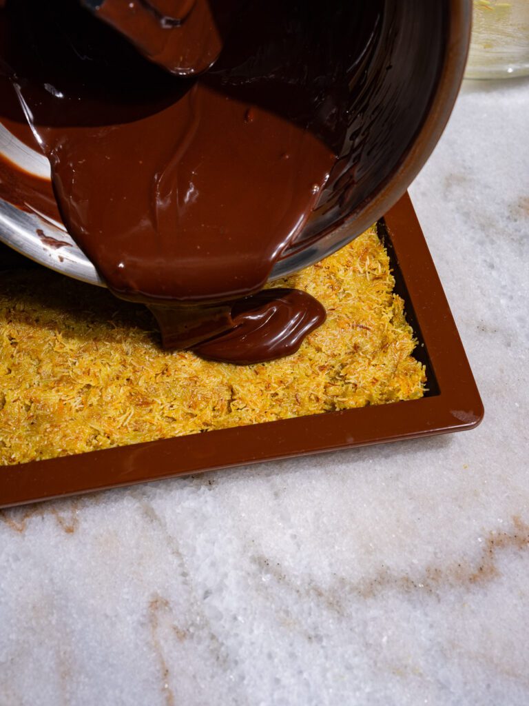 Melted chocolate is poured onto the filling of the Dubai chocolate.