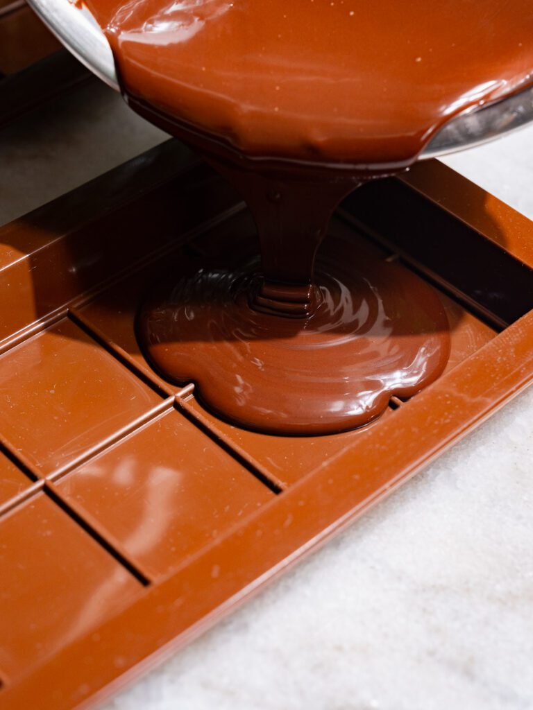 Melted chocolate flows into a mold for a chocolate bar.