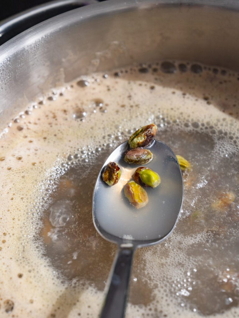 Pistachios are just blanched and lifted from a spoon.