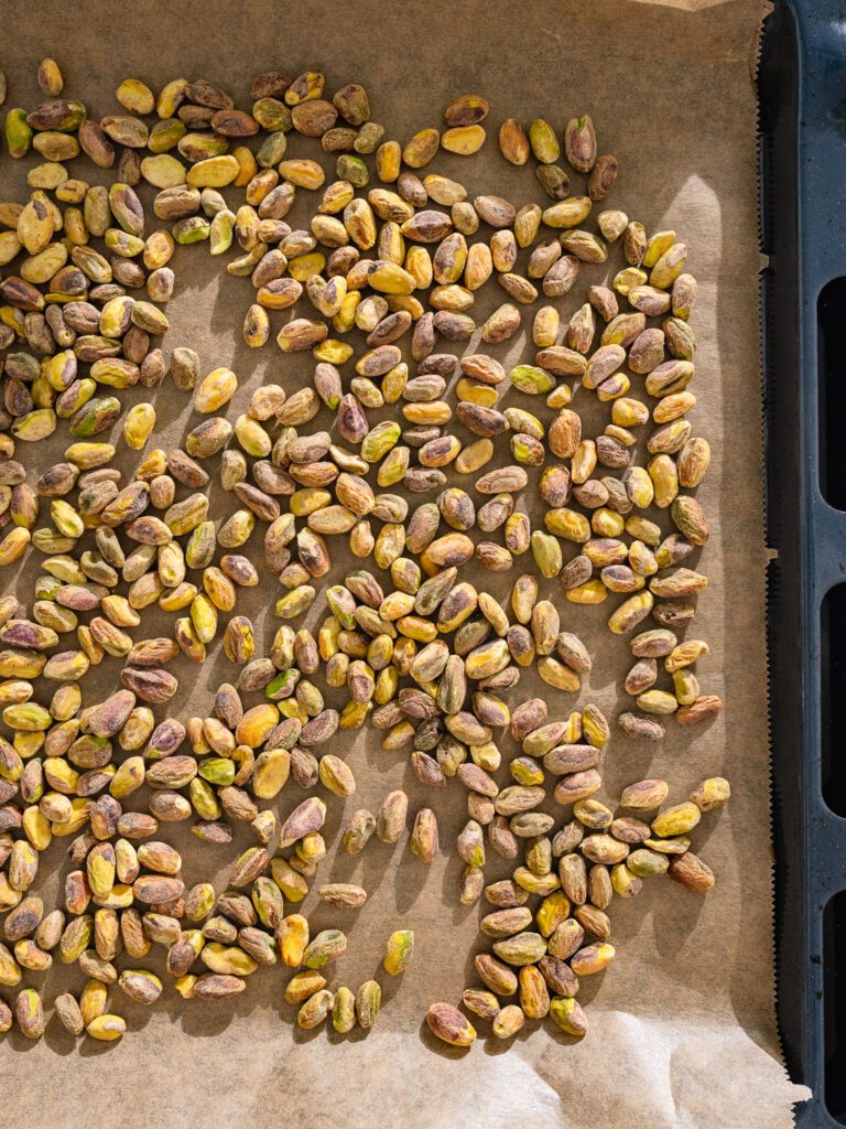 Pistachios are placed on a baking tray to be roasted.